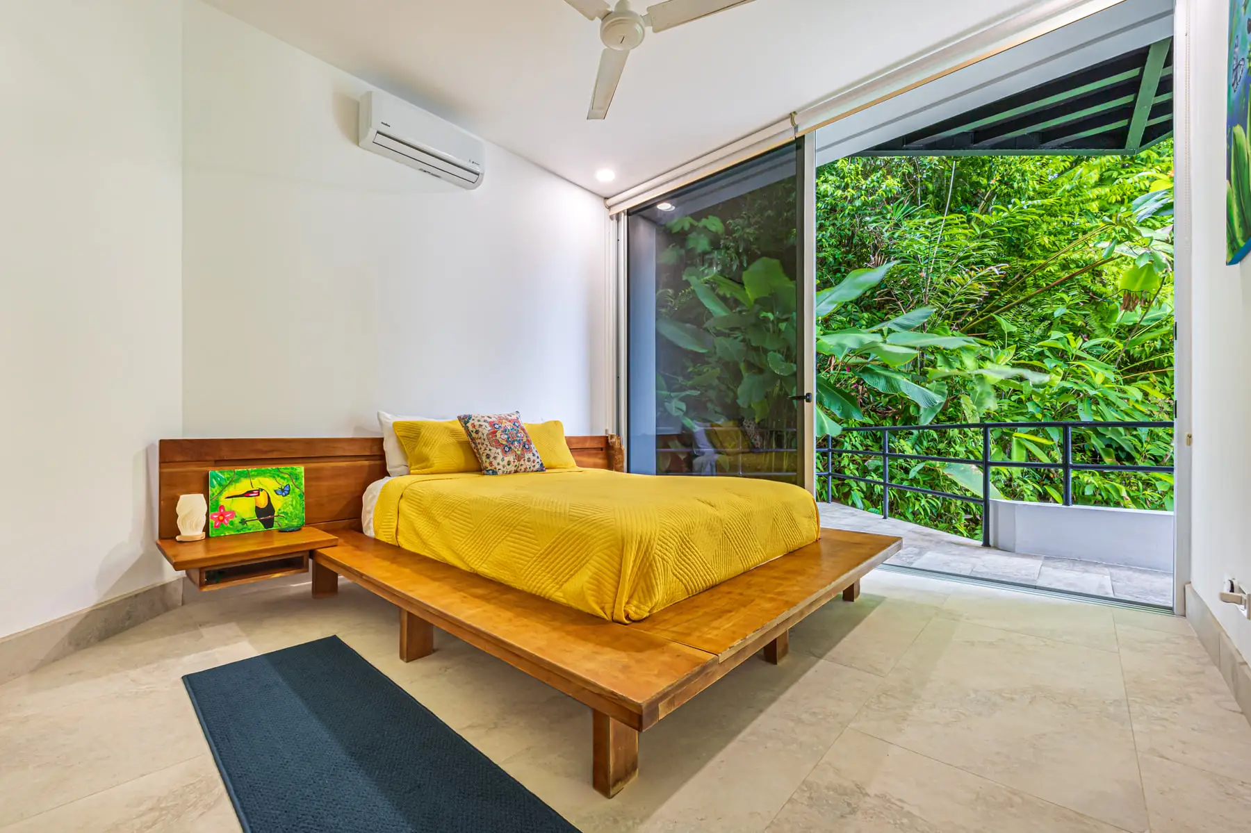 A queen bedroom opening onto the jungle through a full-height sliding door
