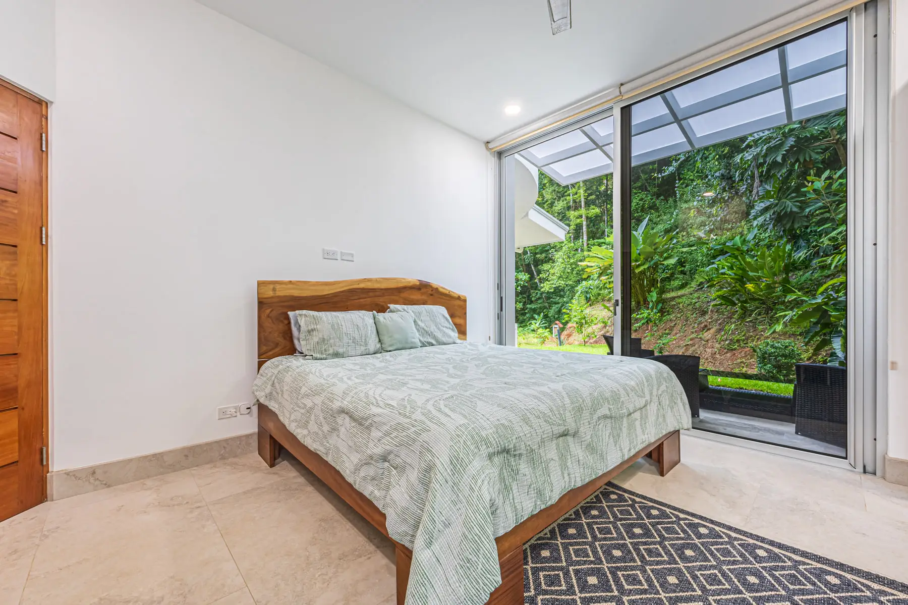 A king bedroom with a wall of glass opening onto its own patio and the jungle