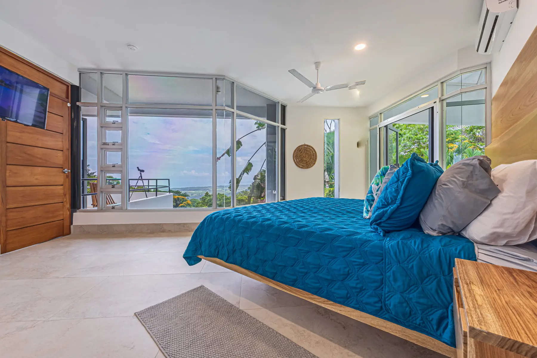 A king bedroom with a corner of glass looking out toward the coast