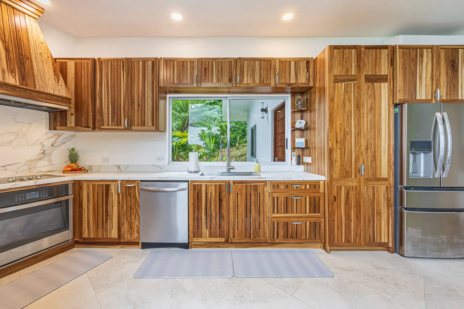 The kitchen, hardwood cabinetry and stone counters, with a window onto the trees