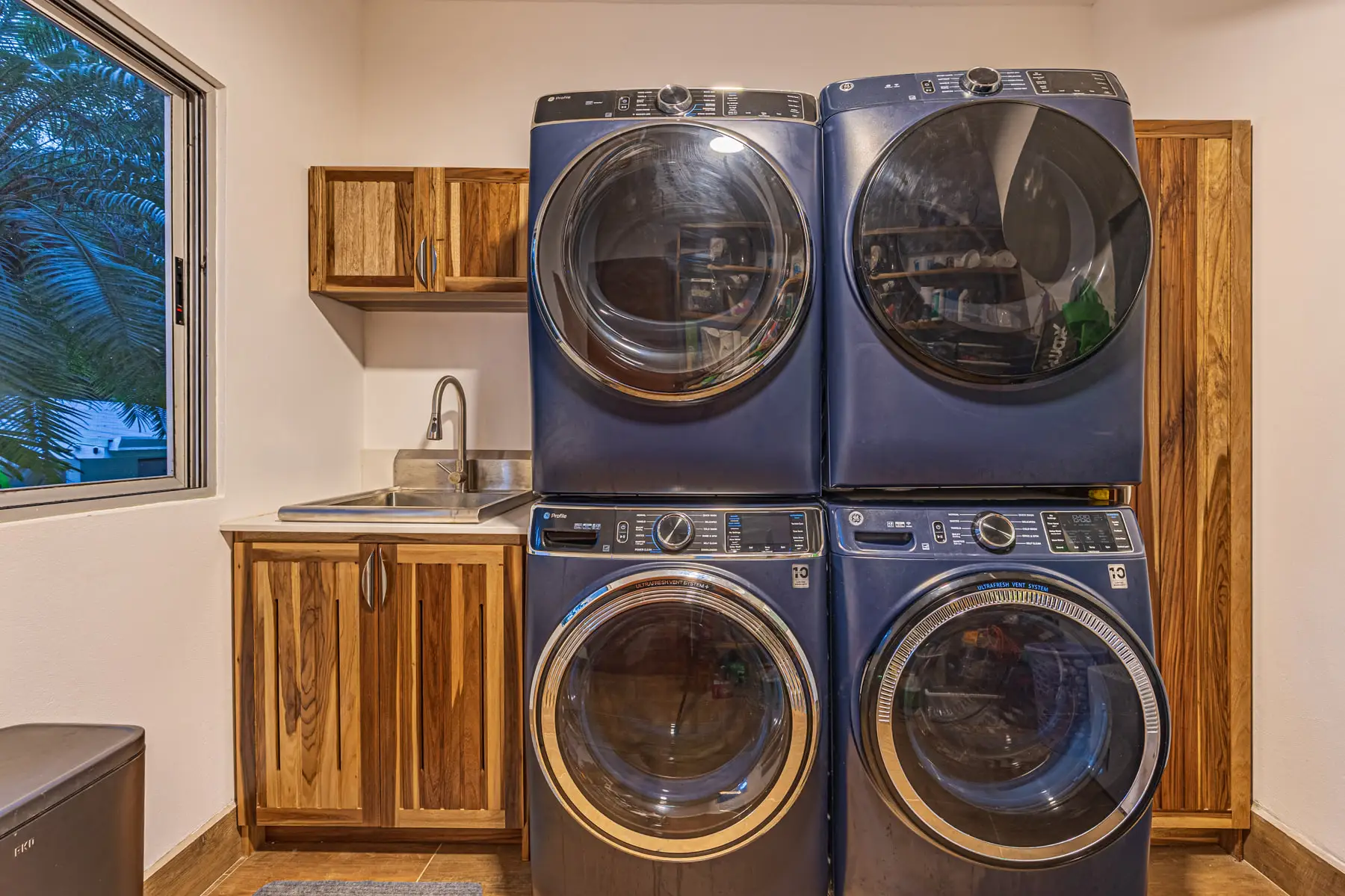 The laundry room with a full-size washer and dryer and hardwood cabinets