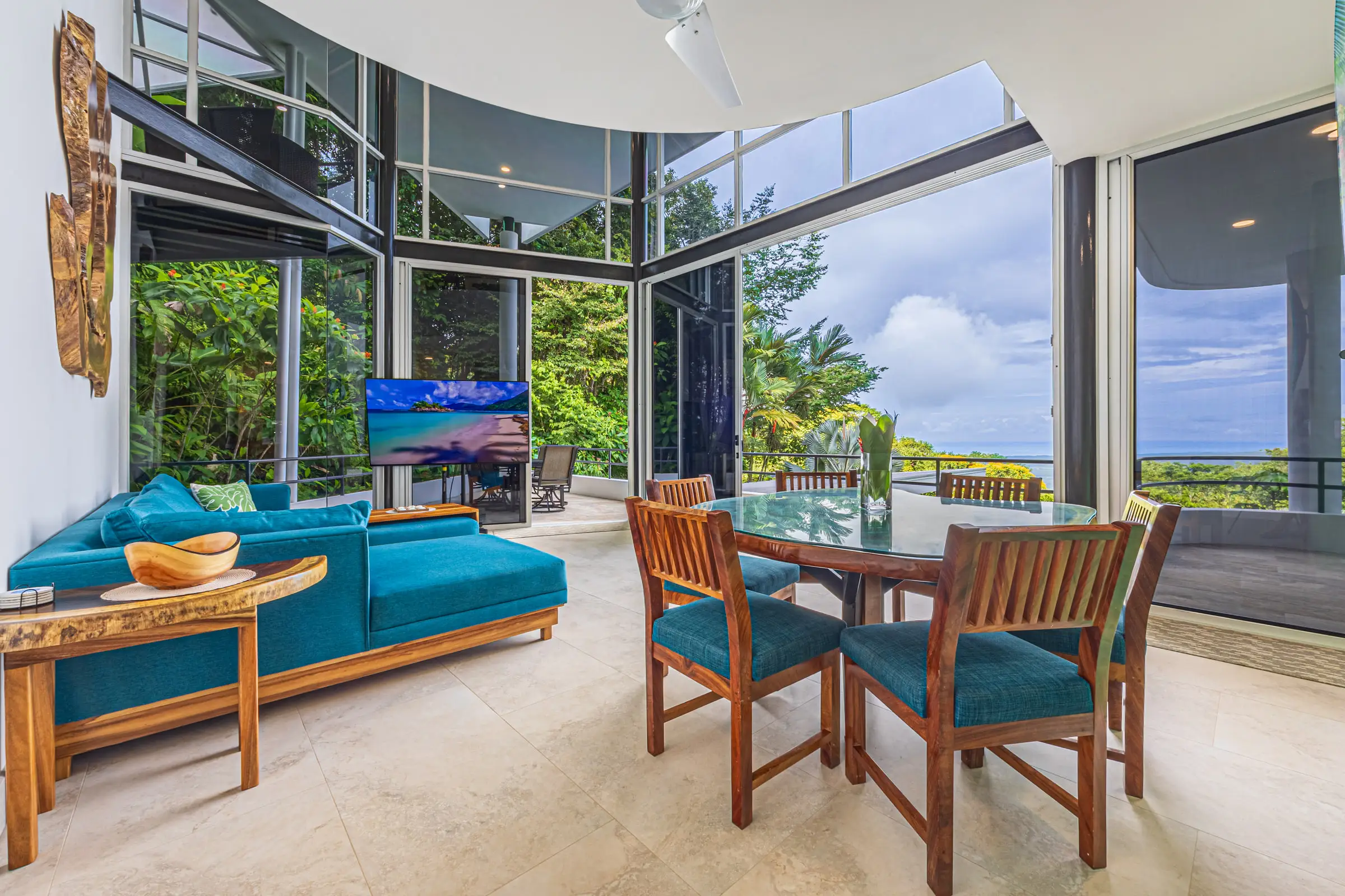 The open living and dining area, glass on two sides, looking out to the pool