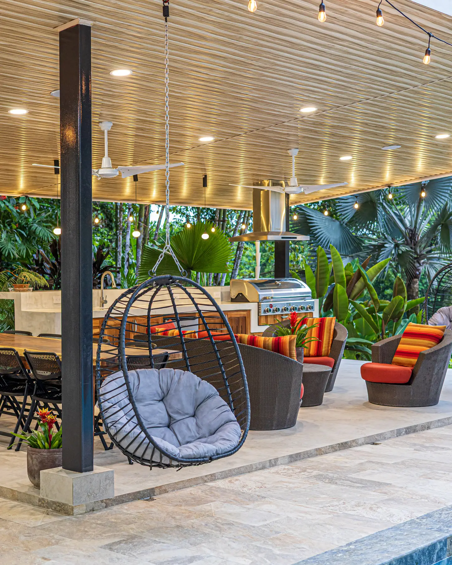 A hanging chair at the end of the covered terrace, looking into the trees