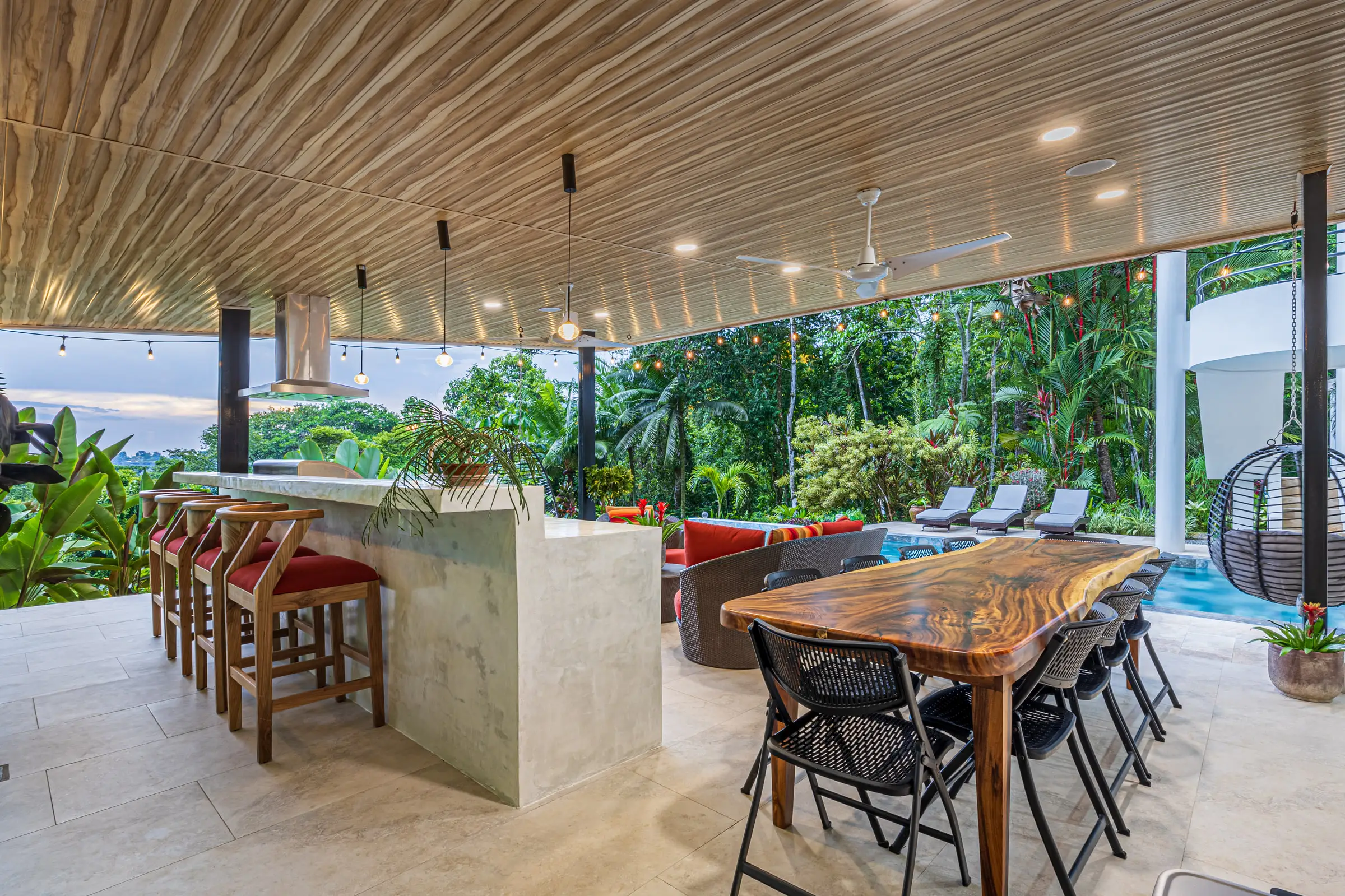 The long outdoor dining table under the slatted wood ceiling of the covered terrace