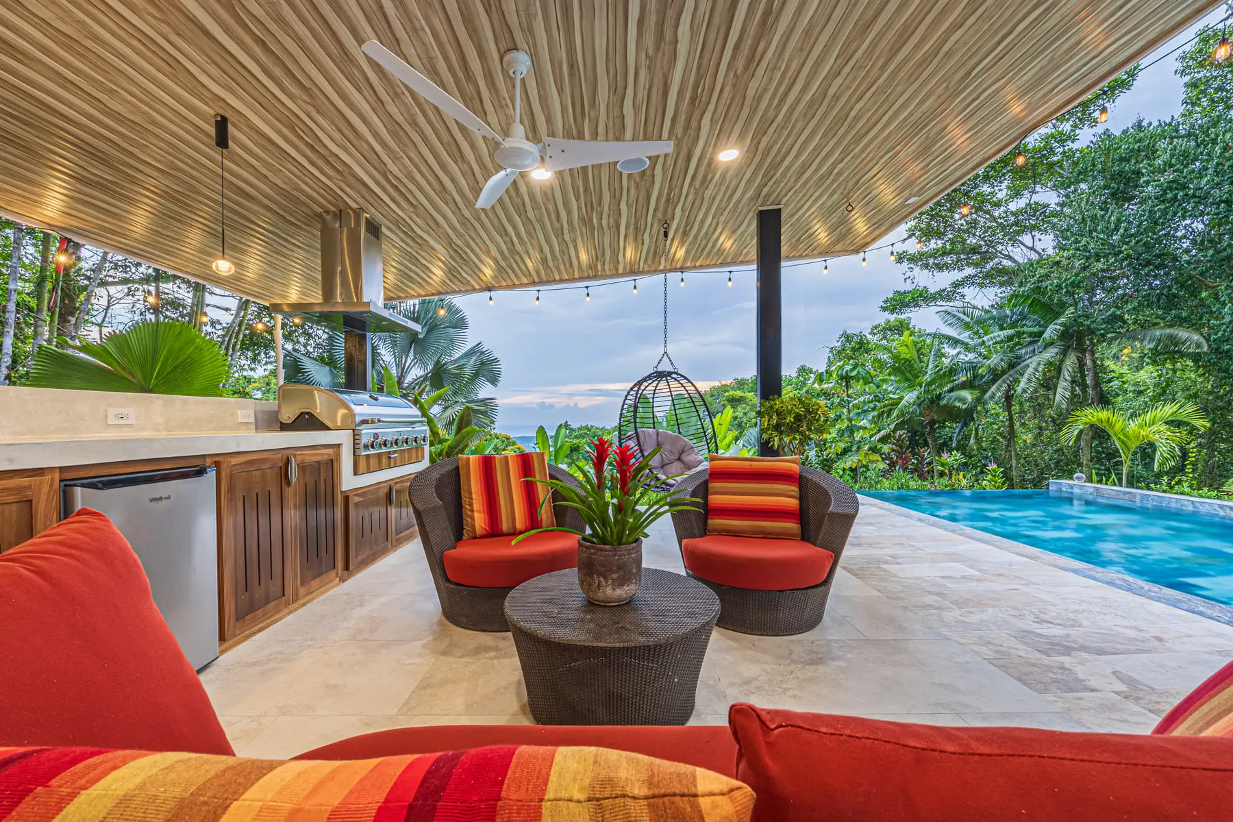 Deep armchairs and a low table on the covered terrace as the light goes