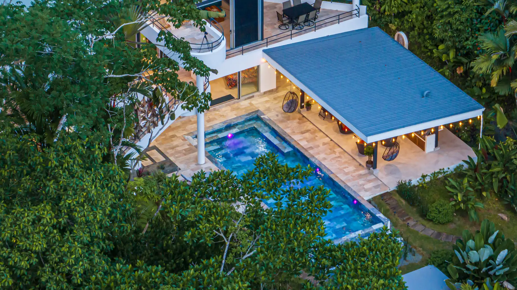 The pool and the covered terrace seen from directly above, surrounded by forest