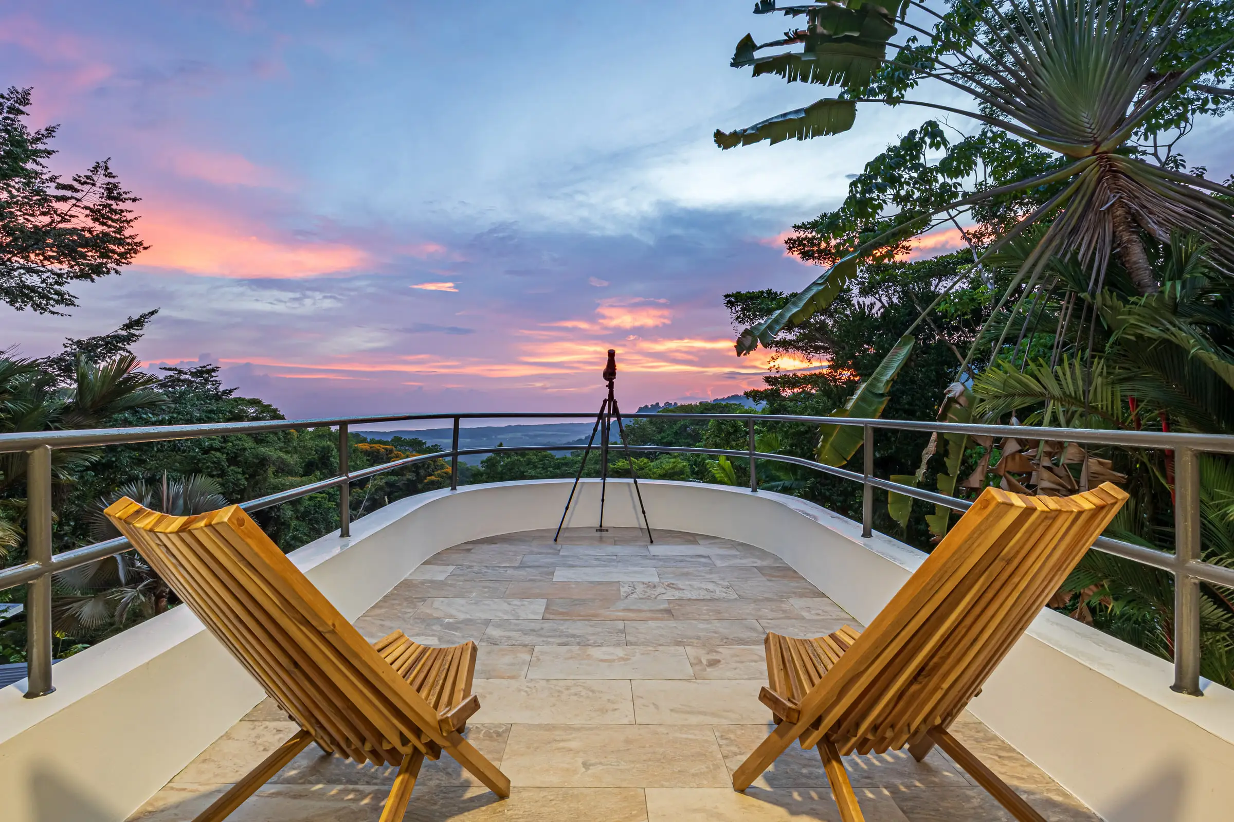 The third-floor deck at dusk, a telescope set up against a pink and violet sky